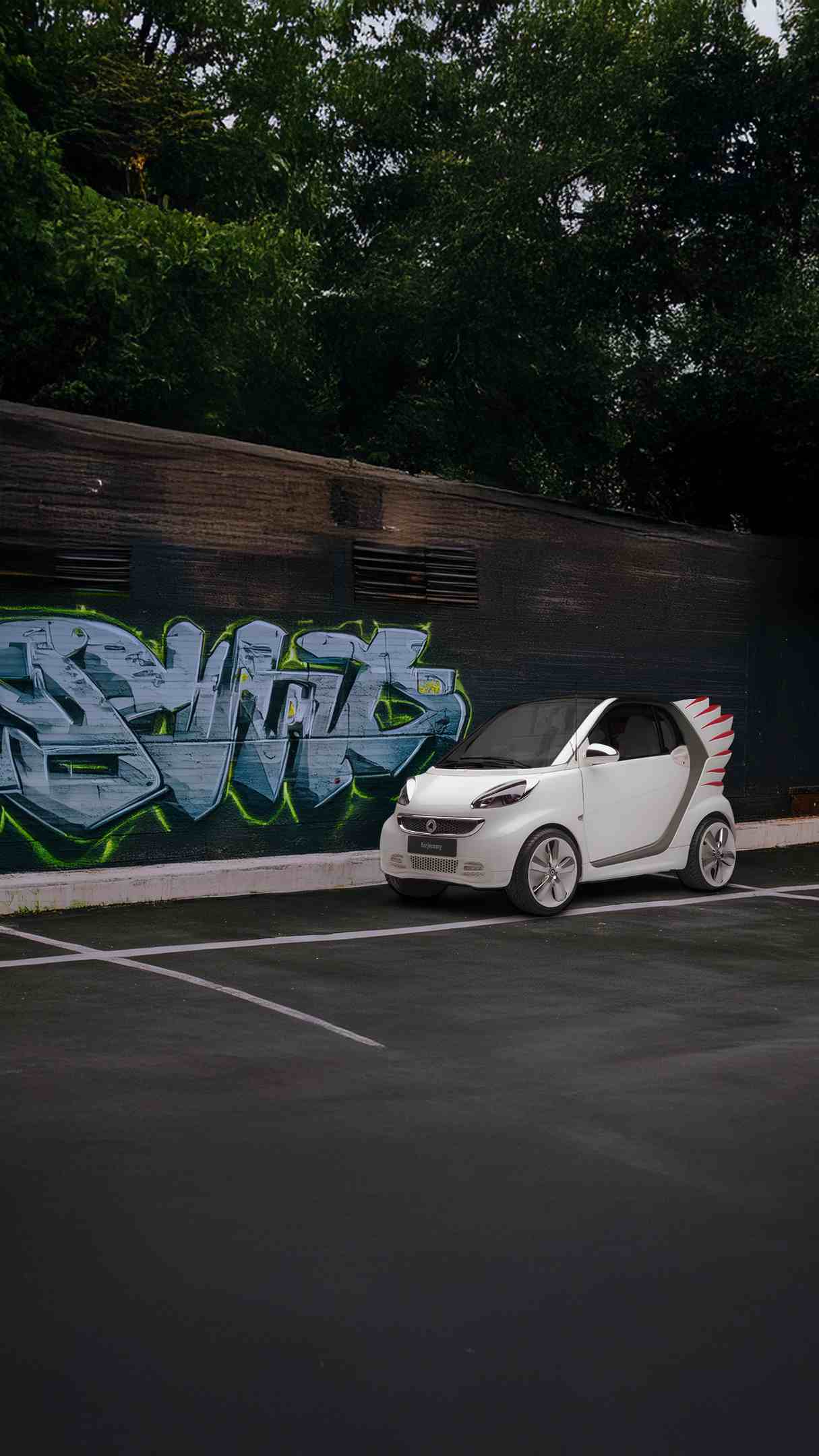 Ein weißer smart forjeremy vor einer mit Graffitti besprühten Wand.